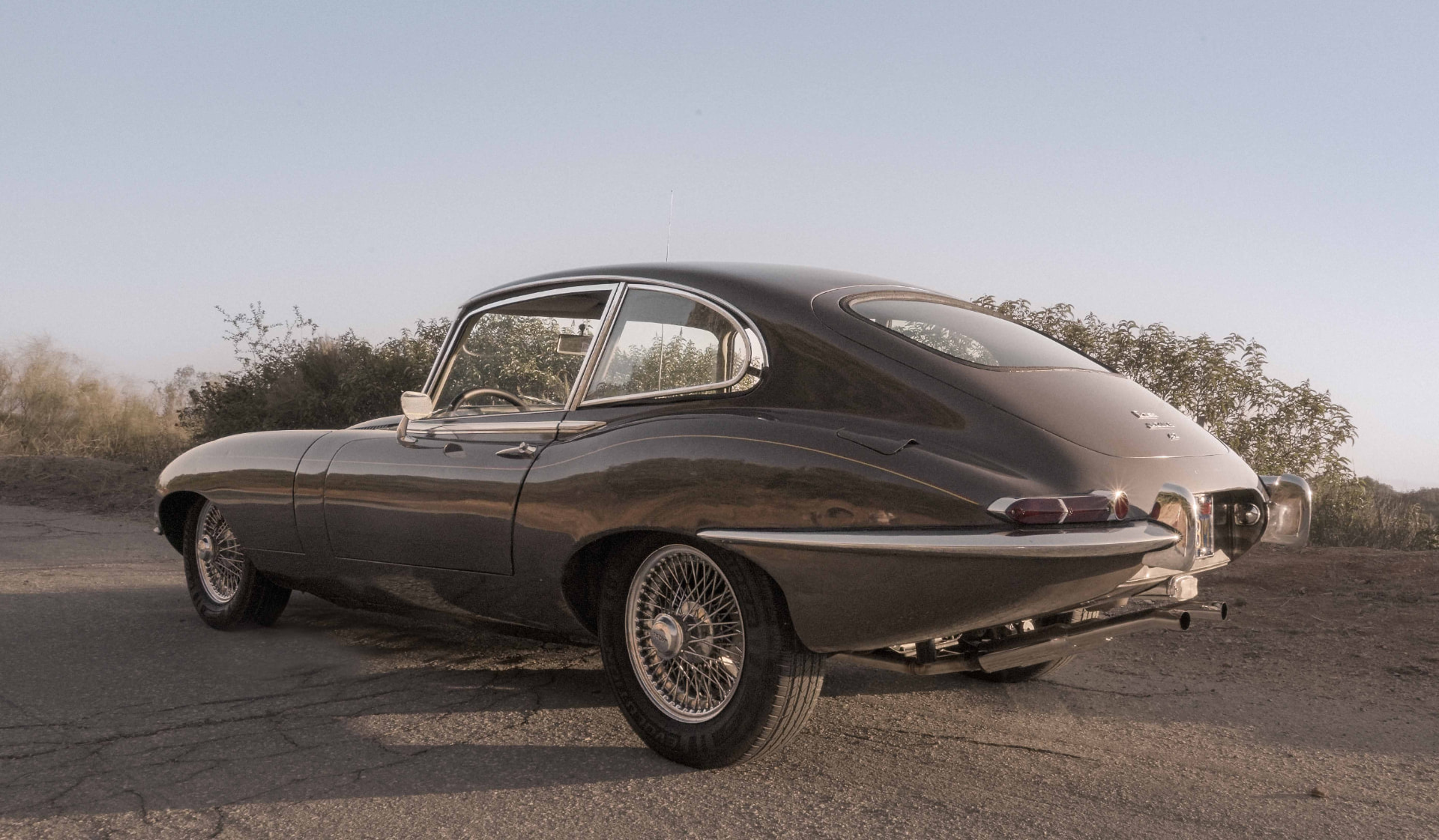 Rear three-quarter view of an original black 1968 Jaguar E-Type coupe in evening light